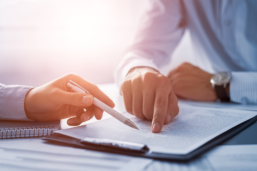 closeup of two hands, pointing on a piece of paper on a clipboard