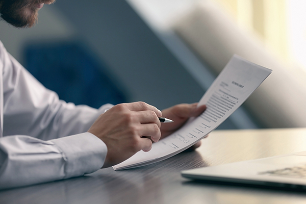 closeup of business man holding a stack of papers and a pen