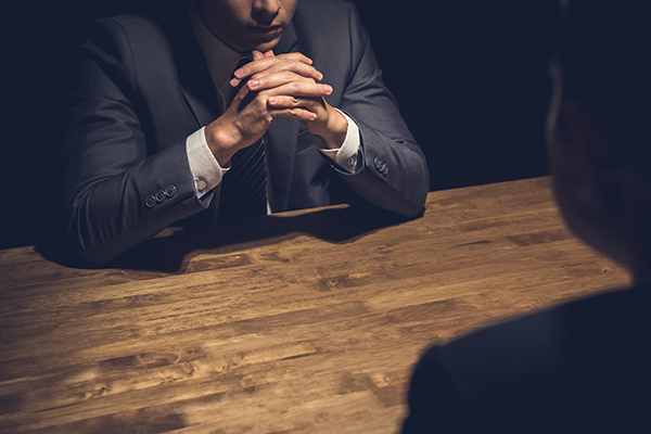 business man crossing his hands, sitting across from another man