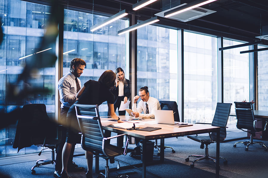 two business men and two business women, in a conference room, around a table talking