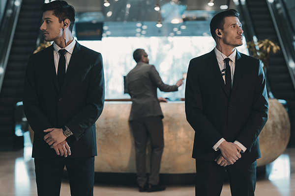 two security guards, crossing arms, standing in front of a business man