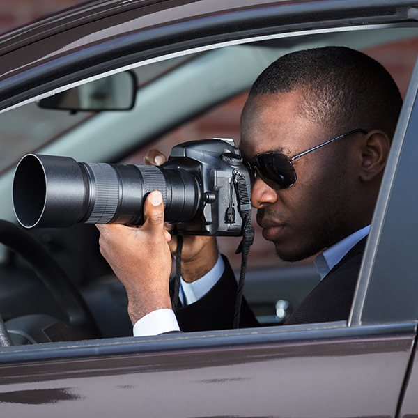 business man, in a car, holding a camera about to shoot a photo