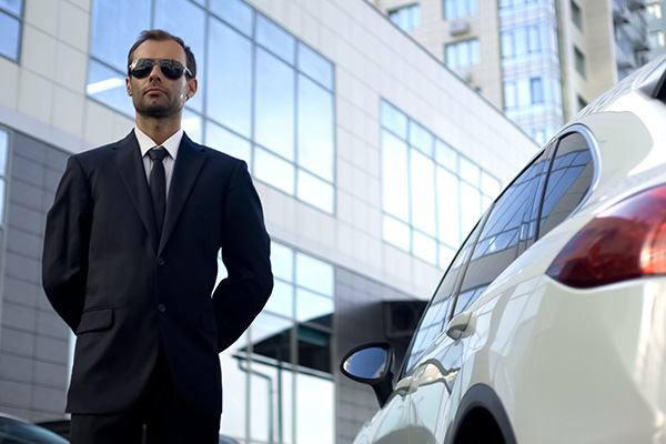 man in a suit standing next to a car