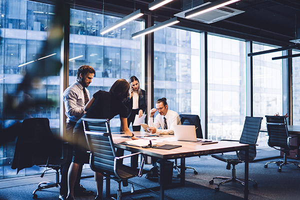 business executives gathering around a desk in a corporate office